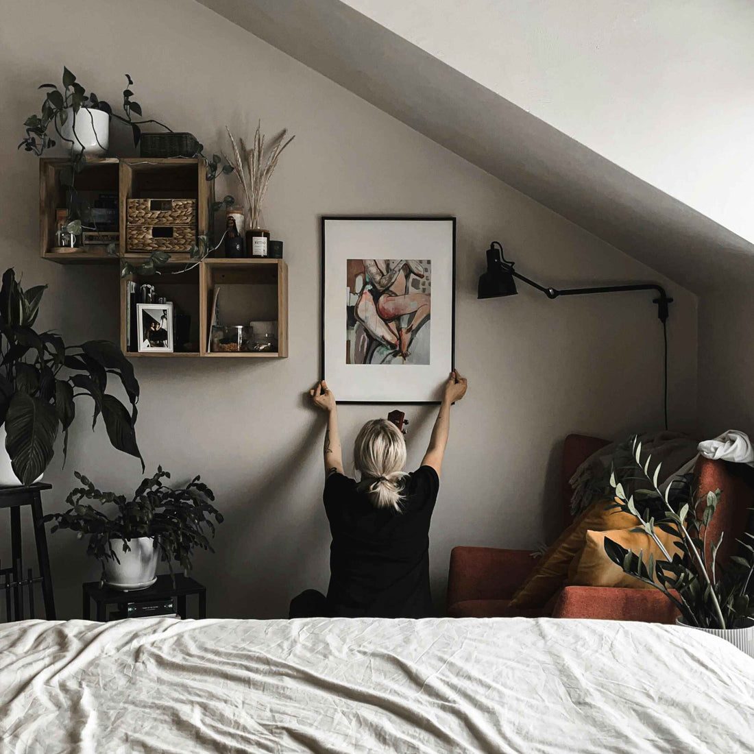 Woman Hanging a Painting in her Bedroom